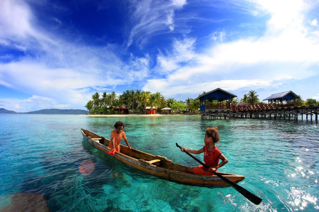 Children paddling near Arborek village jetty in Raja Ampat, Indonesia
